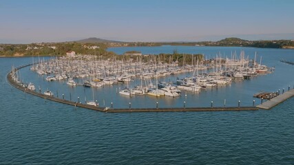 Aerial view of a Bayswater marina filled with yachts and boats docked in Auckland, New Zealand. The boats are moored along piers, creating a dense network of masts and hulls. - Powered by Adobe