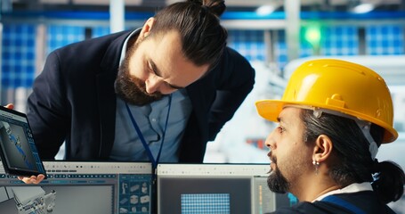 Manager instructs solar panels plant employee on how to use CAD software to optimize layouts....