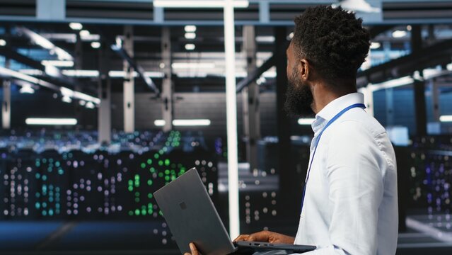 Data center system administrator analyzing infrastructure issues using node tree tools. Man in server hub using AI visualization insights on laptop to optimize system health, camera B
