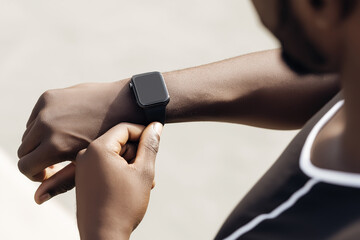 African American man checking smartwatch while jogging outdoors in warm sunset light for fitness technology advertising and healthy lifestyle concept