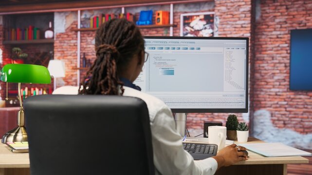 Software developer at PC coding, creating software, implementing algorithms. IT expert in home office working with code editor, building applications, optimizing performance, camera B panning shot