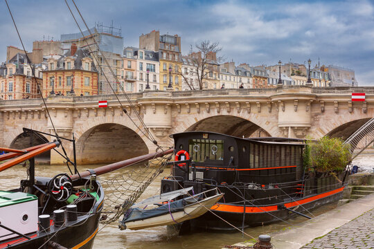 Docked houseboat and old stone bridge over river in historic center of Paris France - Powered by Adobe