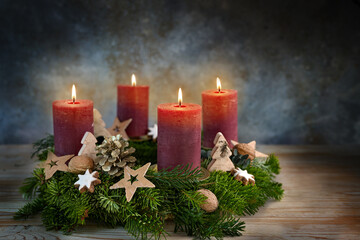 Four red candles on an Advent wreath, all are lit for the fourth advent, small stars, cookies and...