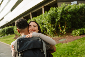 Female athlete laughing with eyes closed while hugging male athlete