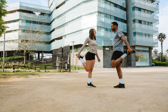 Female and male athletes standing on one leg and holding their legs while smiling