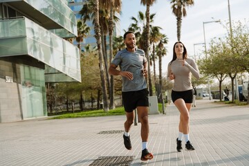 A female athlete looks ahead while running next to a male athlete with his eyes closed