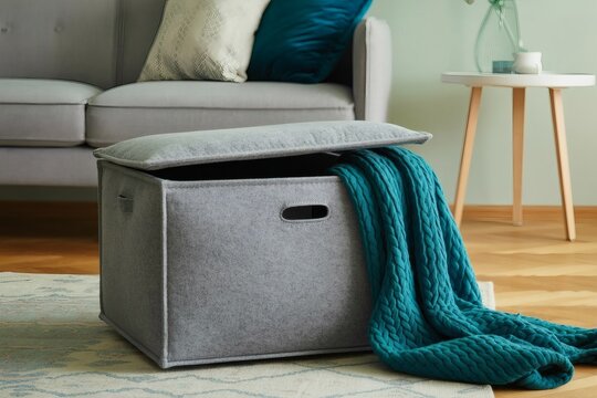 Gray fabric storage ottoman with teal blanket in living room