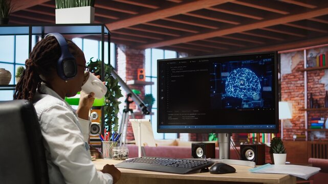 Software developer wearing headphones using computer at home for artificial intelligence computing simulating human brain. IT expert listening music and working with AI deep neural networks, camera A