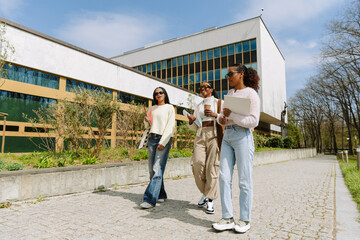 A group of three female students are walking and talking while one of them laughs