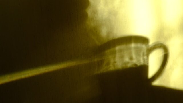 Cup of tea or coffee at the morning, shadow of the woman basking in the sunlight. Abstract backdrop with crossed lines shadows. Tranquility, solitude, peaceful, mindful
