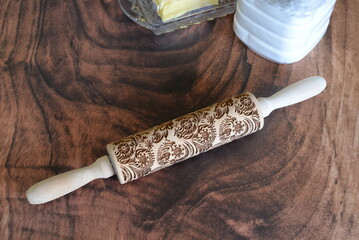 Engraved wooden rolling pin with floral pattern on wood background