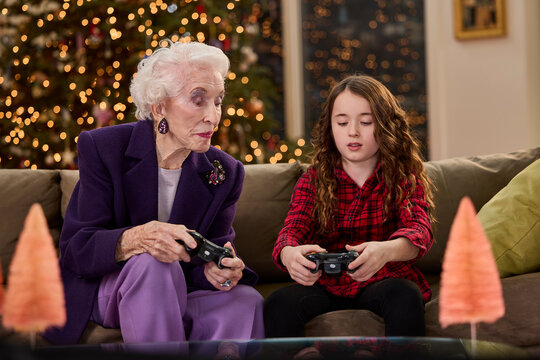 Grandmother and granddaughter bonding over video games during the festive holiday season at home