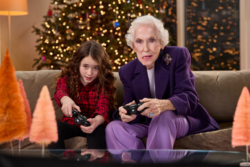 Grandmother and granddaughter enjoying video games together in a festive holiday setting