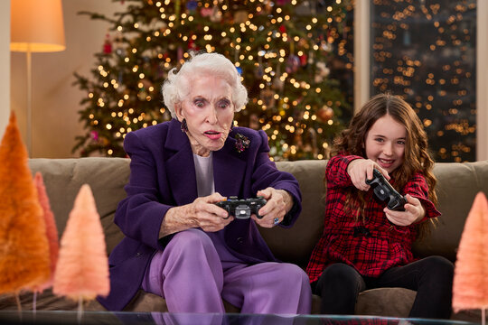 Grandmother and granddaughter enjoying video games together in a festive holiday setting