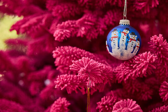 Vibrant pink christmas tree with a festive snowman ornament adds holiday cheer