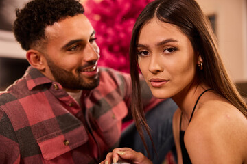 Couple poses together indoors with vibrant pink flowers creating a romantic backdrop behind them