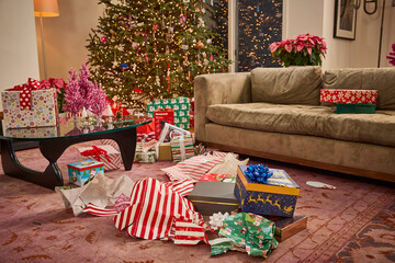 Festive living room with illuminated Christmas tree and unwrapped presents scattered across the floor