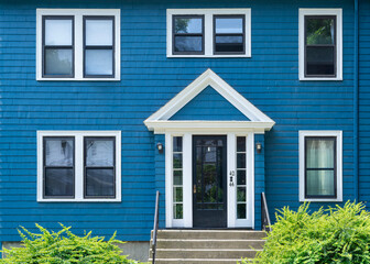Vibrant blue house facade with white pediment and shingle siding in Boston, Massachusetts, USA
