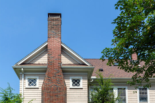Elegant red brick chimney centered on a classic beige family house in Newton, Massachusetts, USA
