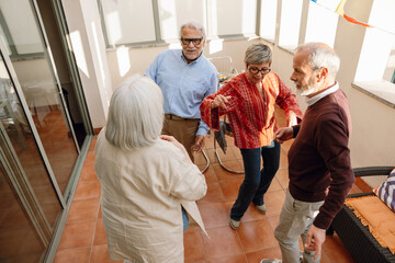 A group of three friends are dancing while two of them listen to a female friend standing next to...