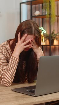 Young woman at home works on laptop reads game loss and failed bet notice and sighs feels upset and low. Caucasian girl at table looks down frowns and pauses typing tries to calm mood and accept news