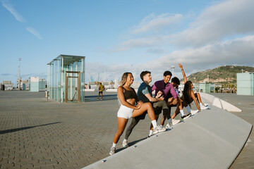 A group of five athletes stretch their legs while three of them laugh