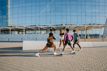 A group of five athletes stand in a circle while warming up and stretching