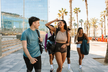 A female and male athlete walk and laugh as a group of three athletes walk behind them