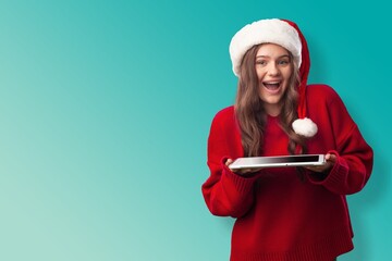 Girl in santa hat holds digital tablet Buying Christmas gifts