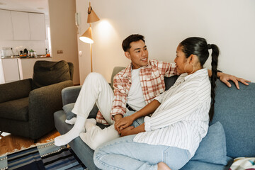 Man smiling and listening to woman while they hold hands and sit on sofa