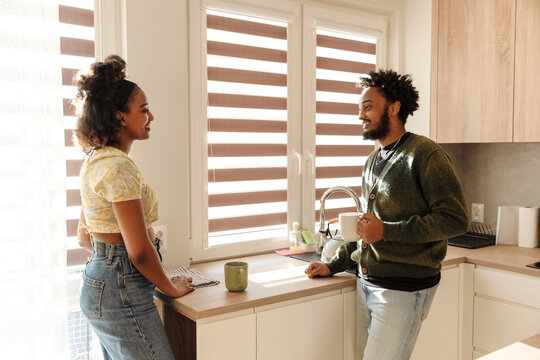 Female and male musicians standing at a table laughing while he holds a cup