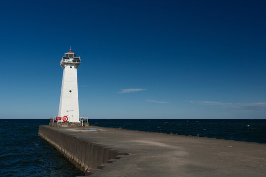 Low angle image of the concrete and stone pier leading to the Sodus Point Lighthouse on Lake Ontario in New York State on a beautiful afternoon