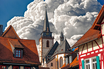 Kirche "St. Ursula", ein Wahrzeichen des Ortes Oberursel im Vordertaunus, Hessen, Deutschland, ragt zwischen historischen Altstadth&auml;usern empor, mit dramatischem Himmelshintergrund