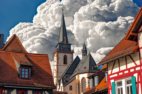 Kirche "St. Ursula", ein Wahrzeichen des Ortes Oberursel im Vordertaunus, Hessen, Deutschland, ragt zwischen historischen Altstadth&auml;usern empor, mit dramatischem Himmelshintergrund
