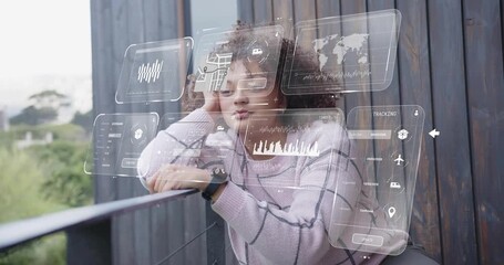 AR panels appearing, woman leaning balcony gesturing at charts, checking smartwatch for tech data - Powered by Adobe