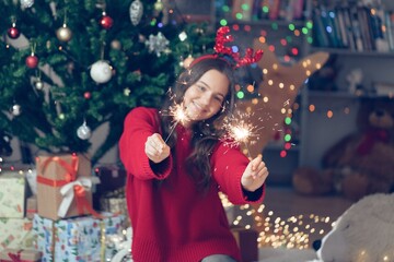 Happy funny child girl with fire sparklers in Christmas background