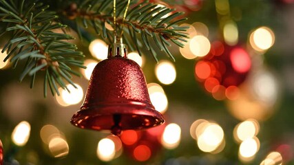 Close up of a red Christmas bell ornament hanging on a tree branch with bokeh lights. - Powered by Adobe
