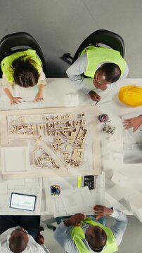 Vertical Video Top down view zoom in of real estate professionals using architectural software to refine housing layouts and 3D models. Development team collaborates on zoning regulations and