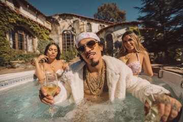 Rapper man in jacuzzi with women drinking champagne