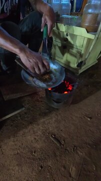 Cinematic vertical footage of a vendor grilling kerak telor at night. Videography of street food being prepared by the vendor in 4K resolution footage.