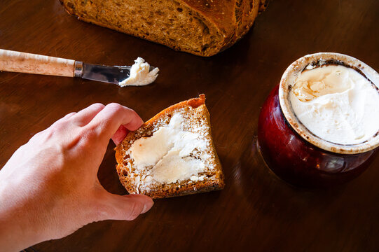 A person picking up a slice of buttered sourdough bread