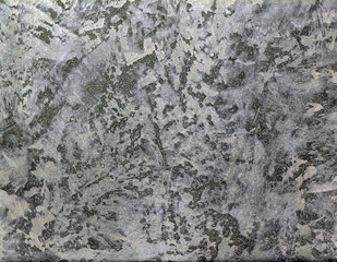 Close-up of a gray textured surface with irregular patterns and layered details, resembling aged stone or industrial metal, creating a rugged abstract background.