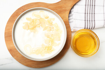 Delicious Greek yogurt with honey and nut flakes served on white table, flat lay