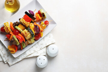 Salt, pepper shakers, oil and tasty grilled vegetables on beige table, flat lay. Space for text