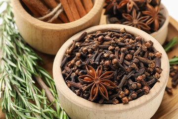 Different spices in bowls and fresh rosemary for mulled wine on table, closeup