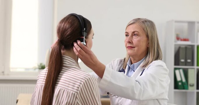 Hearing test. Doctor adjusting patient's audiometric headphones in clinic. Camera moving right