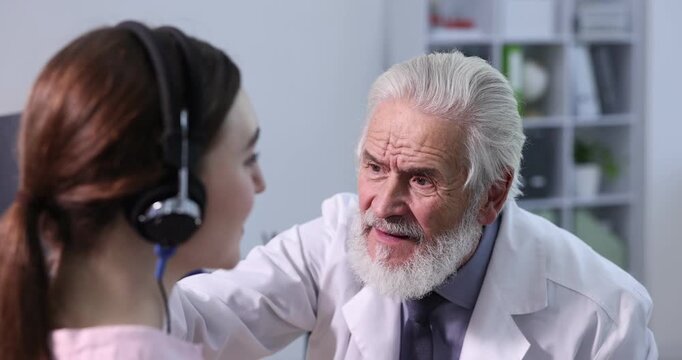 Hearing test. Doctor adjusting patient's audiometric headphones in clinic