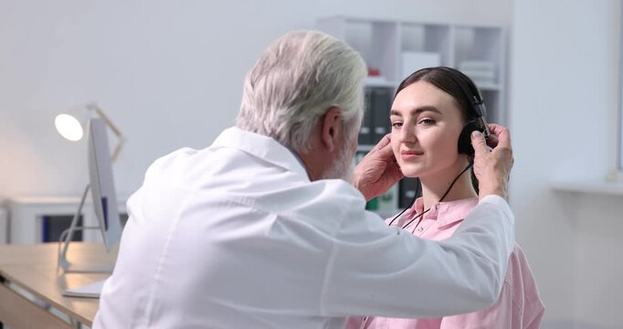 Hearing test. Doctor adjusting patient's audiometric headphones in clinic. Camera moving