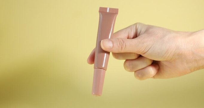 Woman with lip gloss on yellow background, closeup