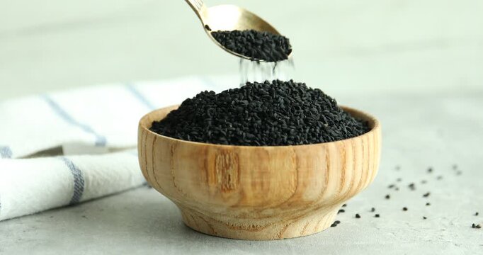 Woman taking aromatic black caraway at grey table, closeup